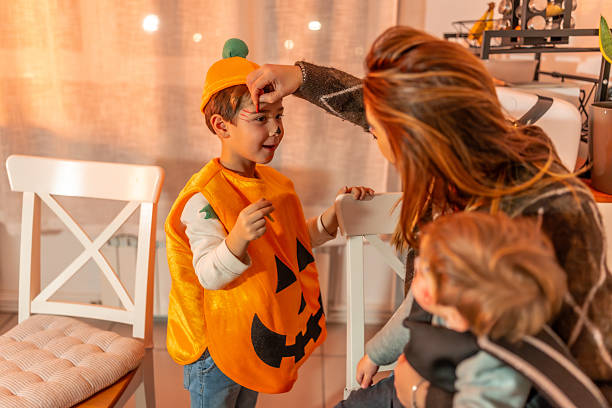 istock Mother applying halloween makeup on her son dressed as pumpkin 2231922603