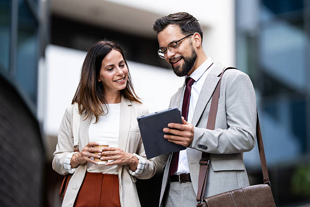 istock Business partners using tablet and having a coffee break outdoors 2231934081