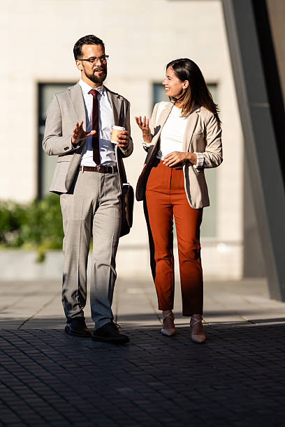 istock Businesspeople walking and talking outdoors during coffee break 2231934173