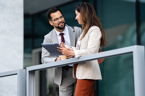 istock Business people using tablet and talking during coffee break outside office building 2231934348