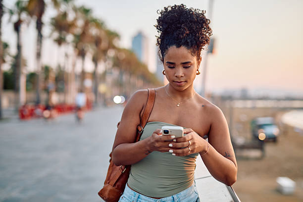 istock Young tourist using smartphone on Barcelona boardwalk at sunset 2231938495