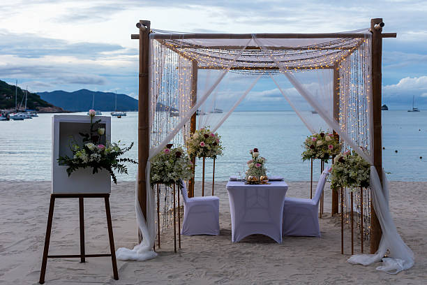 istock Romantic beach wedding setup with floral decorations and elegant drapery under cloudy sky 2231938616