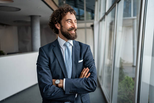 istock Smiling businessman looking out large office window 2231938790