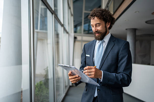 istock Smiling businessman taking notes on clipboard in modern office 2231939030