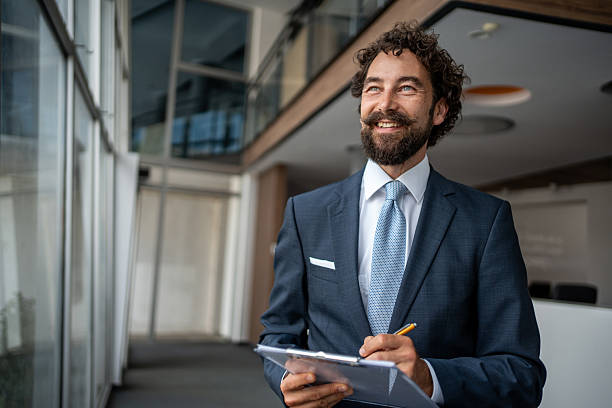 istock Smiling businessman taking notes on clipboard in modern office 2231940297