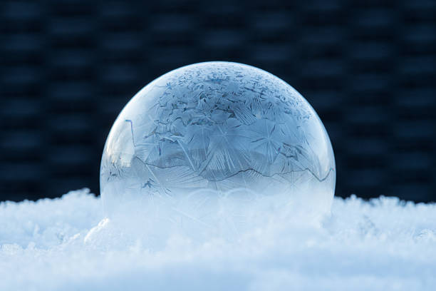 Frozen soap bubble in the snow at sunrise, nature background, calm ice structure