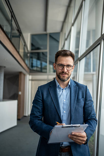 istock Confident businessman writing notes on clipboard in office corridor 2231947934
