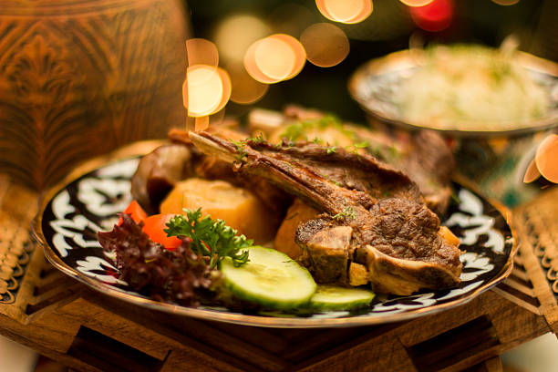 Grilled lamb shashlik served with cucumber, tomato, salad and herbs on an Uzbek ceramic plate, traditional Central Asian cuisine with copy space, menu