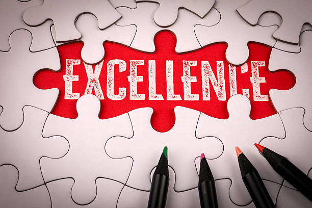 istock Excellence. White puzzle and colored pencils on a red table 2231955788