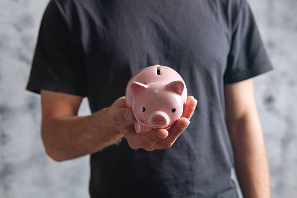istock young man holding a piggy bank 2231956676