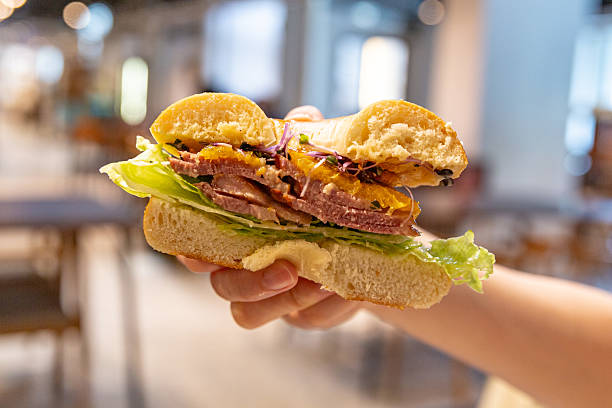 istock Hand holding sandwich pastrami cheddar lettuce microgreens sauce 2231961002
