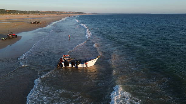 A small dingy beached in the surf on the sandy beach along the Mozambique coast. Photographed along the shore of Inhassoro.