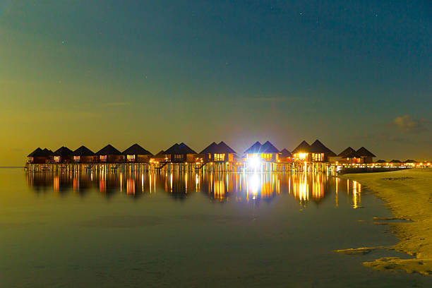 Maldives island lagoon with coral reef and palm trees on calm shore on sunny vacation day in tropical atoll