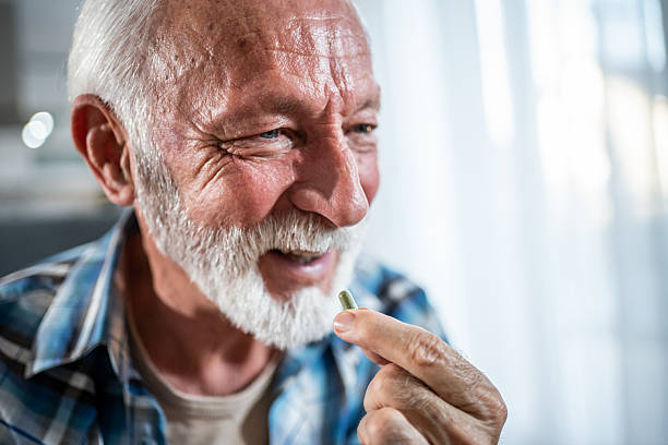 istock Senior man smiling and holding a pill in his hand 2231964958