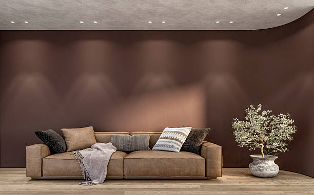 istock Empty, minimalist interior with a brown sofa in front of a brown blank curved wall background and copy space, a potted plant on hardwood floor 2231964989