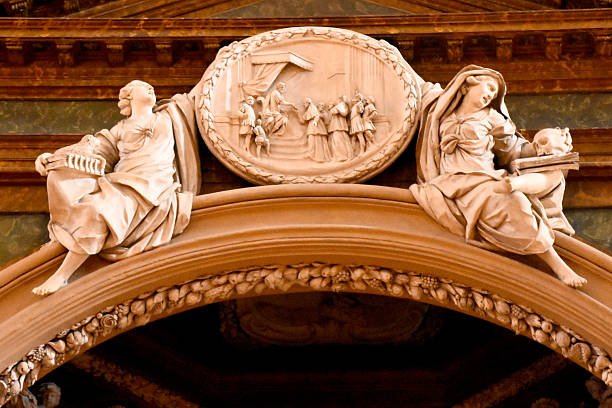 An ornate sculpture featuring two seated allegorical figures above a central relief carving. This detailed Italian artwork is part of a grand, historic archway, showcasing classical architectural and artistic traditions.