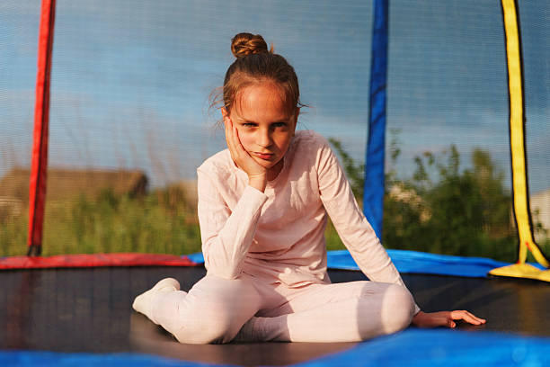 A young girl jumps with joy at a lively playground, her hair flowing freely in the warm breeze of a sunny day
