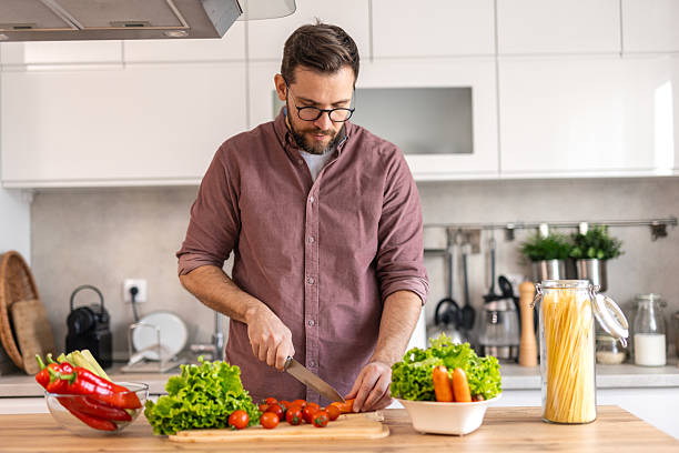 istock Handsome young man man stand at modern kitchen chop vegetables prepare fresh vegetable salad for dinner or lunch, young male cooking at home make breakfast follow healthy diet, vegetarian concept 2231969641