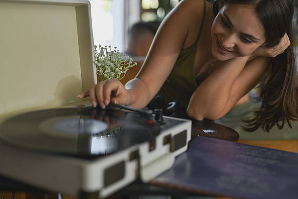 istock Smiling Woman Closely Observing Record Needle While Gently Placing It On Spinning Vinyl 2231971151