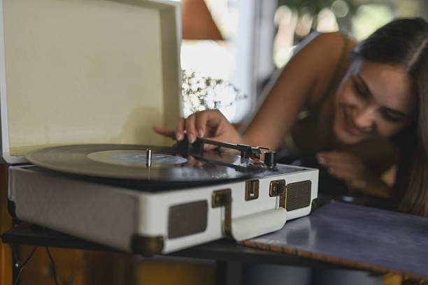 istock Smiling Young Woman Looking Closely At Record Needle While Carefully Placing It On Vinyl 2231971270