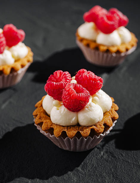 Muffins with raspberries on red sugared background with fresh fruits, decorated with melissa leaves
