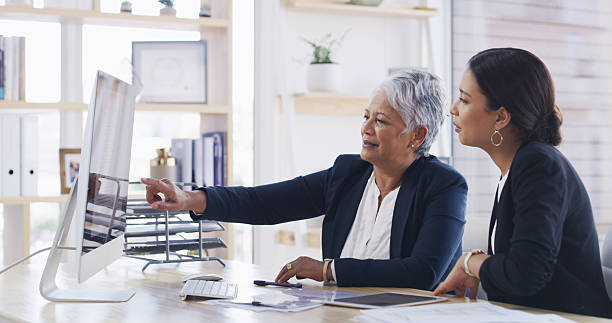 Computer, business women and team planning for accounting, budget or mentor training intern. Screen, meeting and conversation with auditor in office for bookkeeping, investment review or coaching