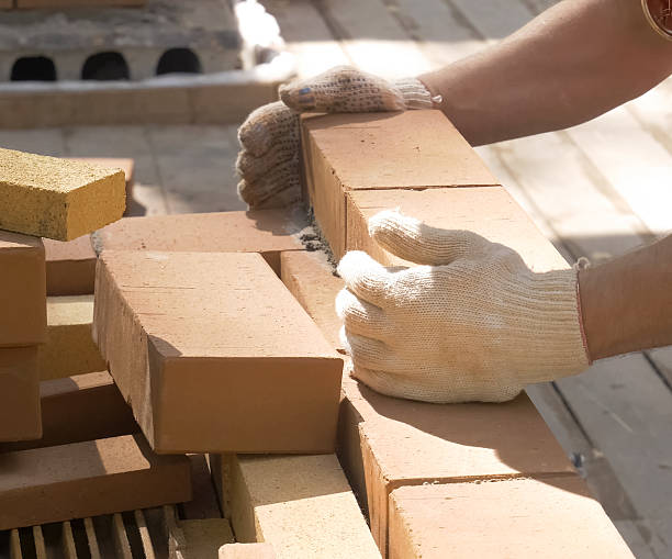 istock A man builds a brick wall. Brick put on the solution. Construction of brick house. 2231978172