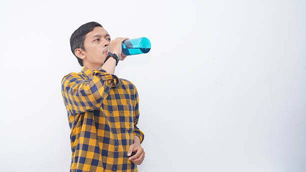 istock Young asian man drinking water on blue bottle isolated 2231979789