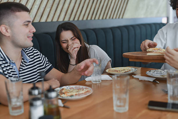 istock Friends Caught In Laughter While Digging Into Delicious Pizza During Relaxed Restaurant Date 2231980378