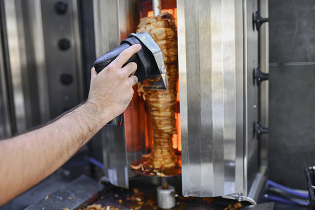 Skilled Male Worker Shredding Doner Meat For Serving In Restaurant Kitchen