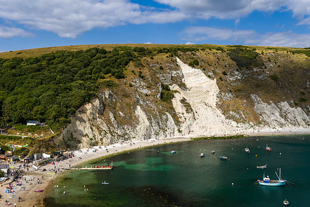 Scenic white chalk cliffs and green hills surrounding Lulworth Cove's clear water