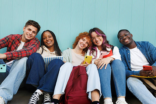 istock Happy students sitting together using mobile phones 2231984664