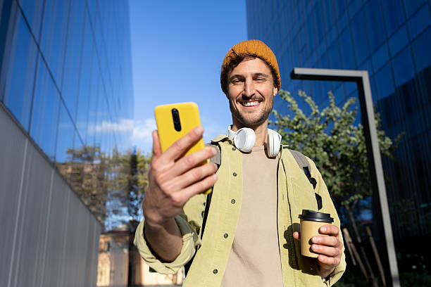 istock Young man using smartphone and holding coffee in city 2231988218