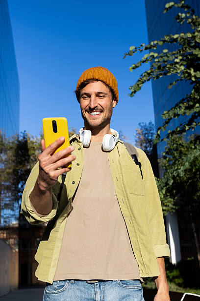 istock Smiling young man using smartphone outdoors in urban setting 2231988223