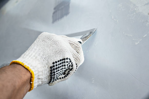 istock Construction worker in gloves using a scraper to scrape and remove all loose paint on the wall during home renovation. Home renovation project 2231988767