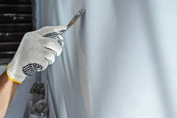 istock Construction worker in gloves using a scraper to scrape and remove all loose paint on the wall during home renovation. Home renovation project 2231988799