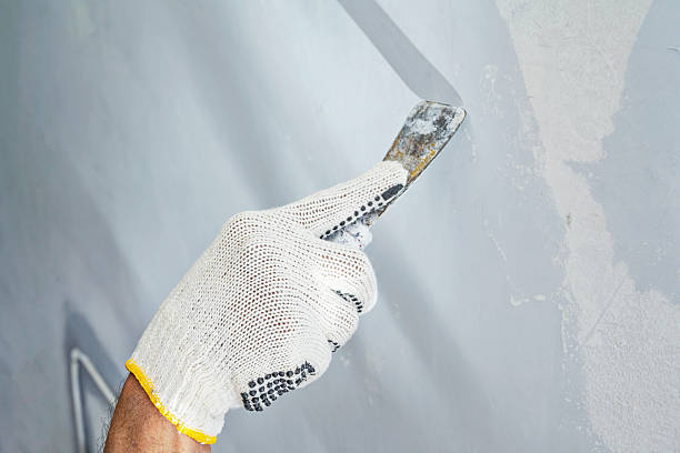 istock Construction worker in gloves using a scraper to scrape and remove all loose paint on the wall during home renovation. Home renovation project 2231988812