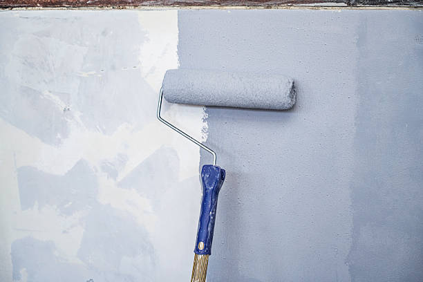 istock Construction worker using a paint roller to apply paint to a wall during home renovation. Home renovation project 2231988856