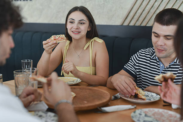 istock Happy Friends Sharing Pizza And Conversation While Sitting At Trendy Restaurant 2231992311