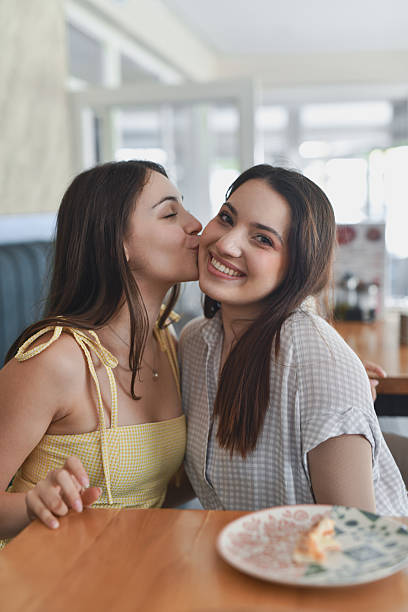 istock Affectionate Female Kissing Friend's Cheek While She Is Looking At Camera With Smile 2231996525