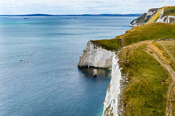 Scenic English coastline with chalk cliffs, rolling green hills, and blue sea in summer