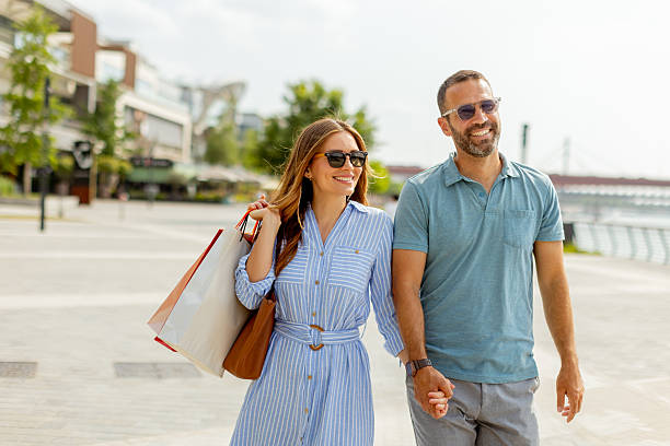 istock Couple enjoying a sunny day in a modern shopping district while sharing laughter and holding hands 2231999747