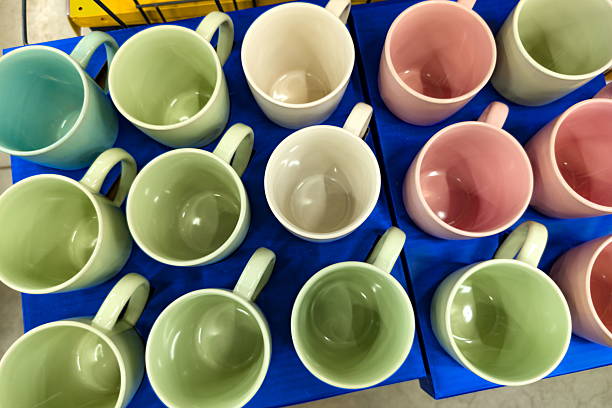 Ceramic mugs in soft pastel colors sit organized on a blue display. The collection includes green, pink, and off-white hues, highlighting the store's playful and inviting atmosphere.