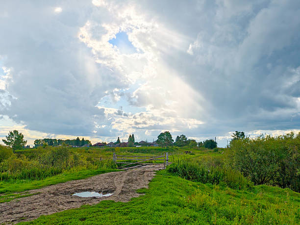 Storm clouds, puddles and mud at a rural road fork - dramatic countryside landscape.
