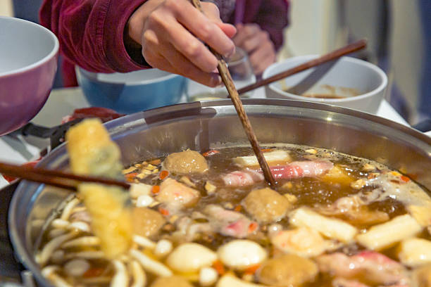istock Close-up people using chopsticks cook meat ingredients bubbling hot pot active dining scene 2232007673