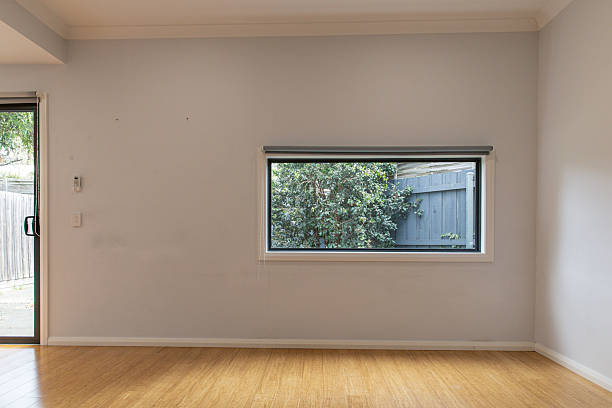 istock Minimalist room light wooden flooring large horizontal window view leafy tree black fence soft natural light 2232008009