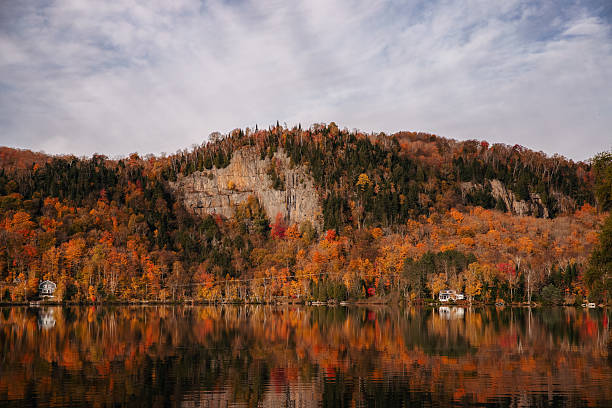 An autumn landscape featuring a mountain lake with a colourful forest in the background, located in Quebec, Canada.