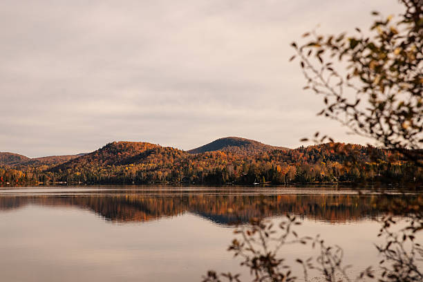 A mountain lake during the autumn season, surrounded by vibrant autumn foliage. Quebec, Canada.