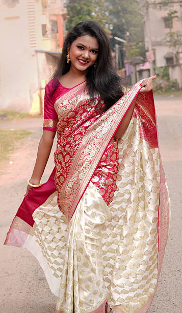 istock A joyful Bengali Indian bride woman is laughing while adjusting her. Beautiful traditional clothing saree and inadian accessories concept. full portrait. 2232013875