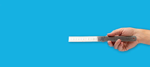 istock Hand holding metal ruler on blue background with copy space. 2232016175
